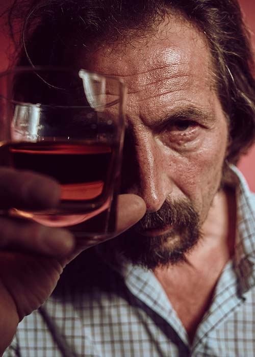 мужчина держит перед собой стакан с алкоголем